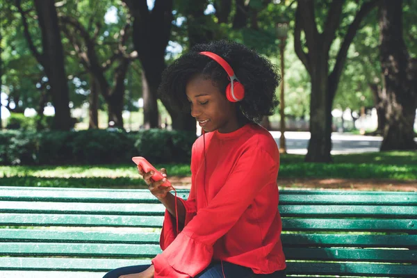 Uma mulher ouvindo música nos fones de ouvido em um parque — Fotografia de Stock