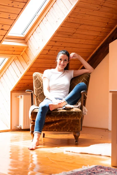 Een mooie vrouw zittend in een fauteuil in een zolder appartement. — Stockfoto