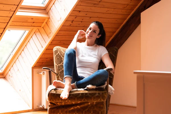 Een mooie vrouw zittend in een fauteuil in een zolder appartement. — Stockfoto