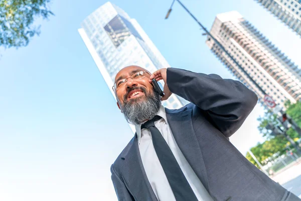 Asiatischer Geschäftsmann telefoniert an der Skyline einer Großstadt Stockbild