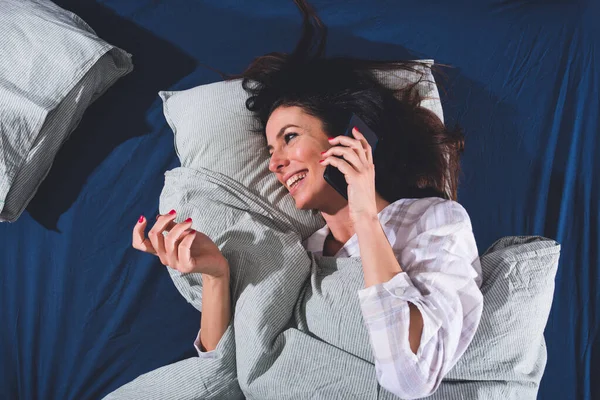 Šťastná mladá žena v posteli mluvící telefon — Stock fotografie