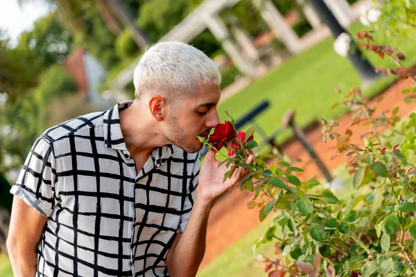 Jovem loira cara cheirando rosa — Fotografia de Stock