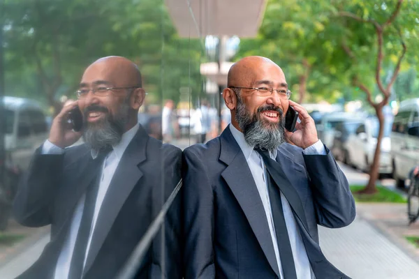 Smiley asiatischer Geschäftsmann telefoniert in einer städtischen Umgebung Stockbild