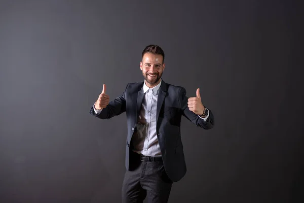 Un hombre de negocios sonriente mostrando el pulgar en un estudio — Foto de Stock