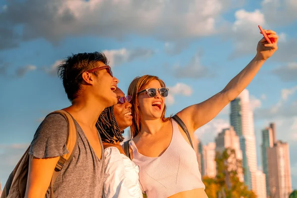 Jóvenes amigos tomando selfies en la orilla del río — Foto de Stock