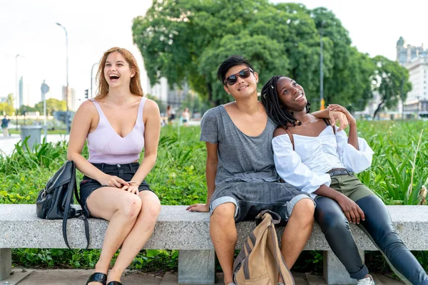 Des amis heureux assis dans un parc — Photo