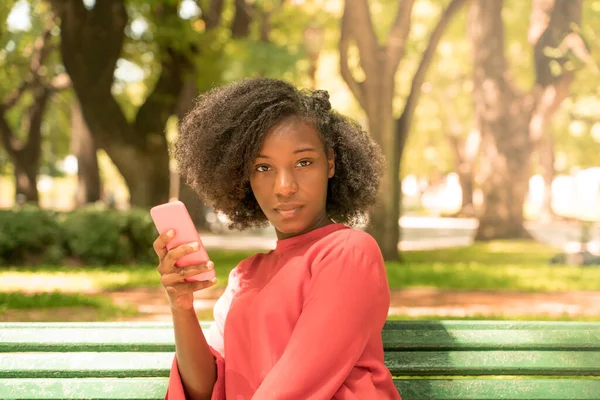 Piękna czarna kobieta używająca telefonu w parku — Zdjęcie stockowe