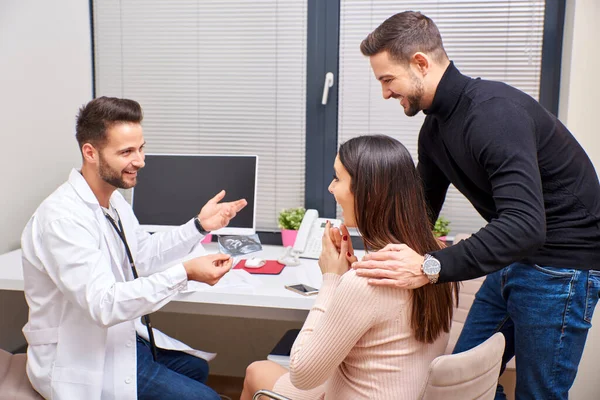 Um médico mostra a imagem de ultra-som para o casal — Fotografia de Stock