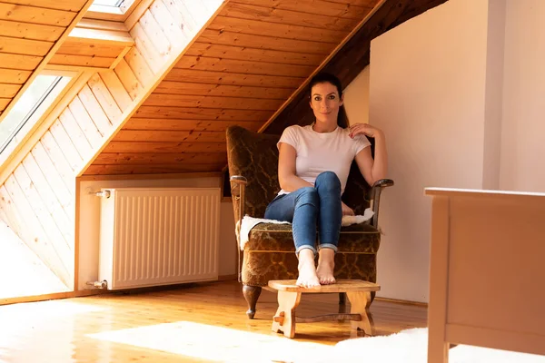 Een mooie vrouw zittend in een fauteuil in een zolder appartement. — Stockfoto