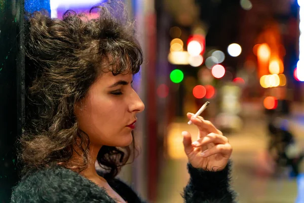 Roken latijn vrouw met een sigaret in haar hand op straat 's nachts — Stockfoto