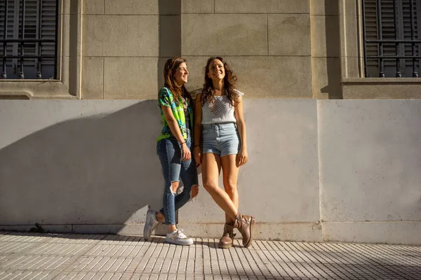 Mujeres amigas de pie en la pared de la calle —  Fotos de Stock