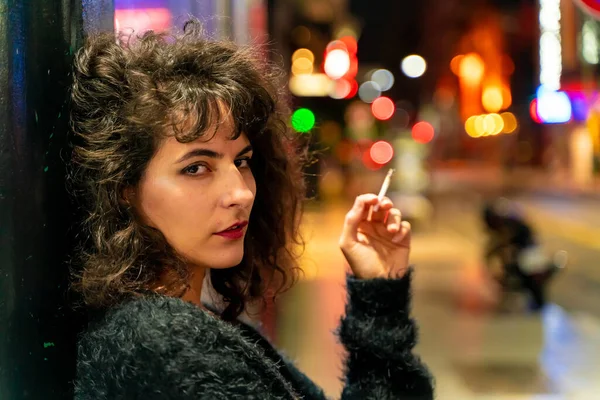 Fumar mulher latina com um cigarro na mão na rua à noite — Fotografia de Stock