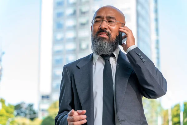 Азіатський бізнесмен розмовляє по телефону в міському середовищі. Стокове Фото