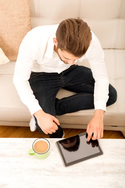 Young man with tablet on couch — Stock Photo, Image