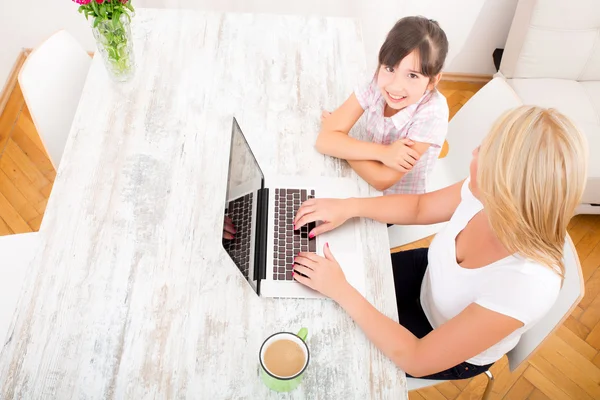 Mãe e filha com um laptop em casa — Fotografia de Stock