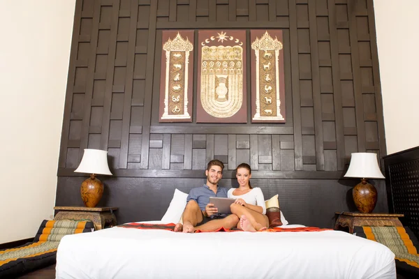 Casal jovem usando um Tablet PC em um quarto de hotel asiático — Fotografia de Stock
