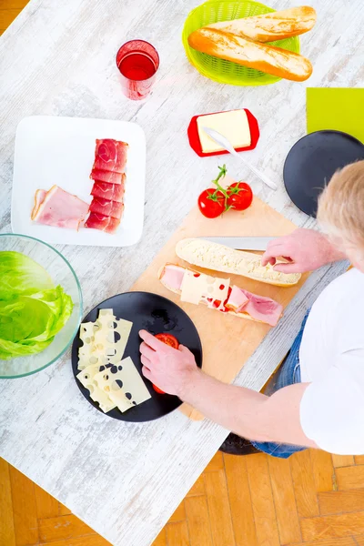 Jeune homme préparant un sandwich — Photo