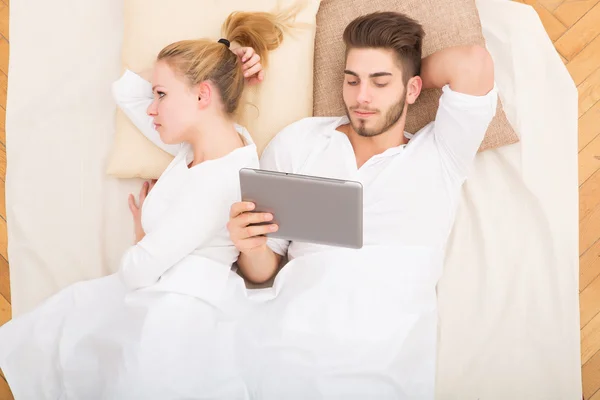 Cuplu tânăr cu un PC tabletă în pat — Fotografie, imagine de stoc