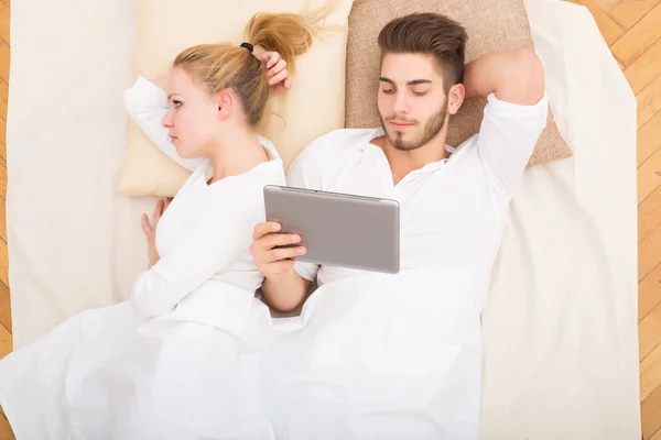 Jeune couple avec une tablette PC au lit — Photo