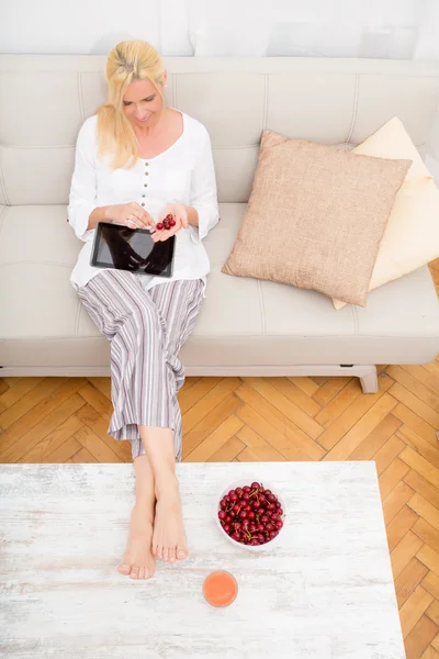 Vrouw met tablet pc op de bank — Stockfoto