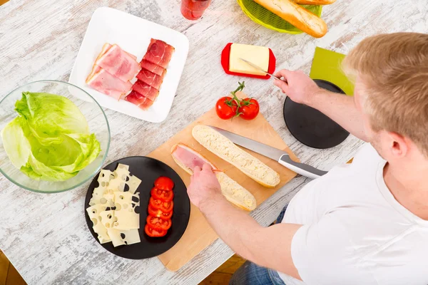 Jongeman bereidt een broodje voor — Stockfoto