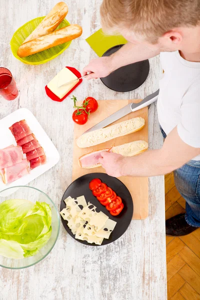 Jongeman bereidt een broodje voor — Stockfoto