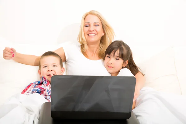 Yatakta bir dizüstü bilgisayar kullanarak çocukları ile anne — Stok fotoğraf