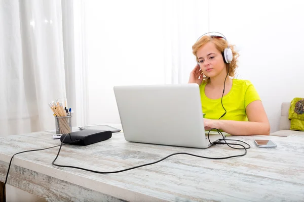 Молодая женщина plus size слушает аудио во время работы над ноутбуком — стоковое фото