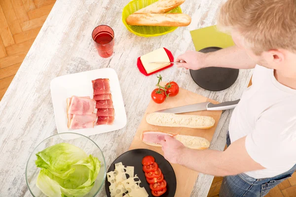 Jongeman bereidt een broodje voor — Stockfoto