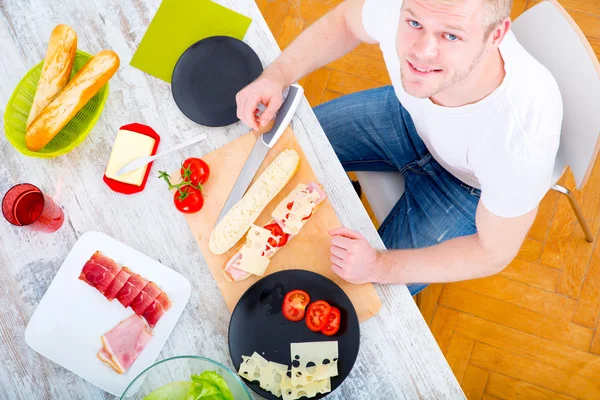 Jongeman bereidt een broodje voor — Stockfoto