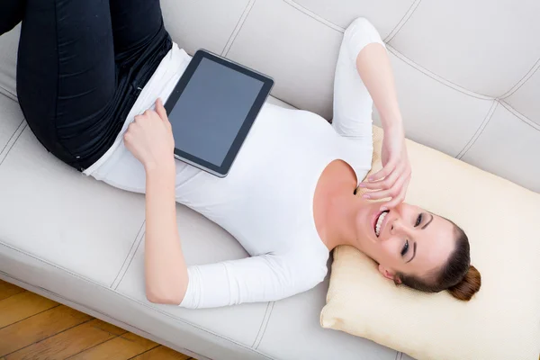 Jeune femme avec une tablette PC sur le canapé — Photo