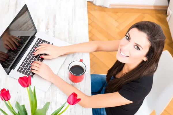 Jonge mooie vrouw met behulp van een laptop thuis — Stockfoto