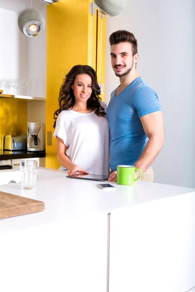 Unga par använder en Tablet PC i köket hemma — Stockfoto