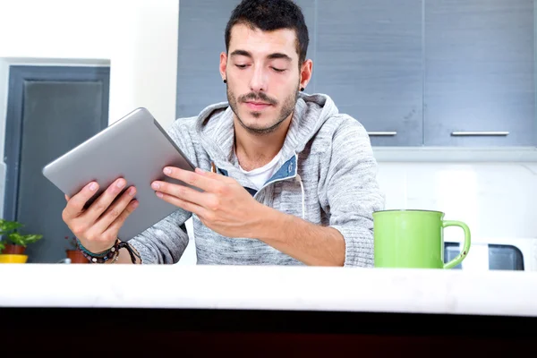 Jovem com tablet na cozinha — Fotografia de Stock