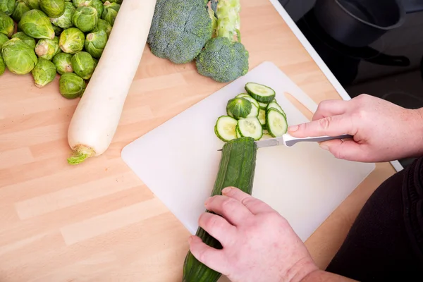 Woman cutting cucumber — Stock Photo, Image