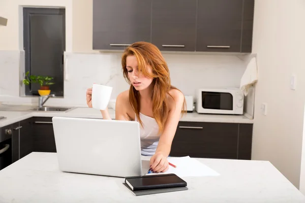 Рыжая девушка пьет кафе на кухне — стоковое фото