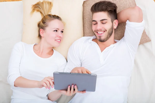 Junges Paar mit Tablet-PC im Bett — Stockfoto