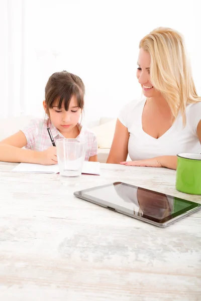 Moeder haar dochter met het huiswerk helpen — Stockfoto