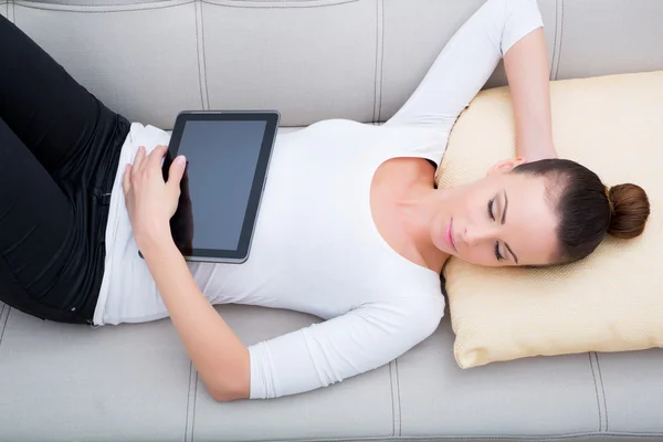 Mujer joven con un Tablet PC en el sofá — Foto de Stock