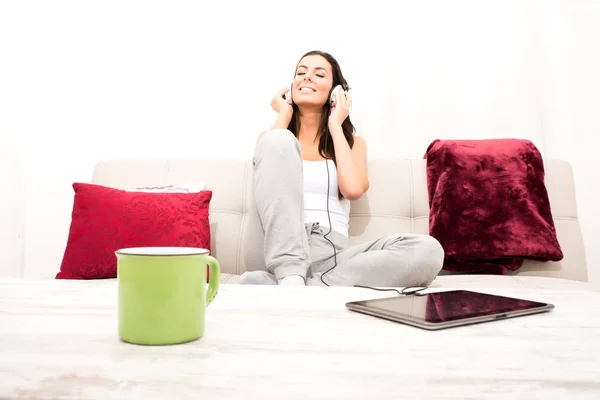 Молодая красивая женщина слушает музыку с планшетного компьютера в доме — стоковое фото