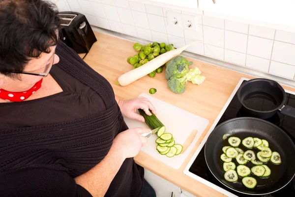 Woman cutting and frying cucumber — Stock Photo, Image