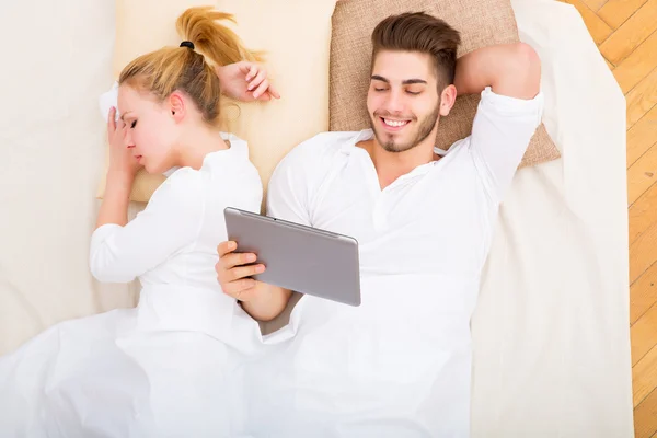 Jong koppel met een tablet-pc in bed — Stockfoto