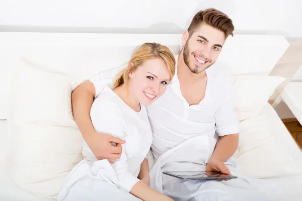Νεαρό ζευγάρι με ένα tablet pc στο κρεβάτι — Φωτογραφία Αρχείου