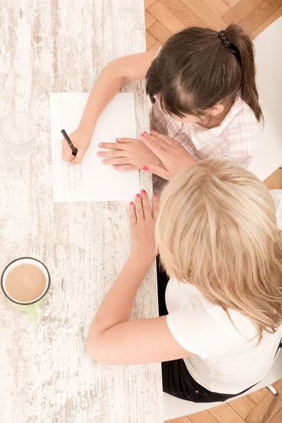 Mother helping her daughter with the homework — Stock Photo, Image