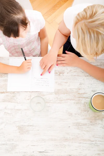 Moeder haar dochter met het huiswerk helpen — Stockfoto