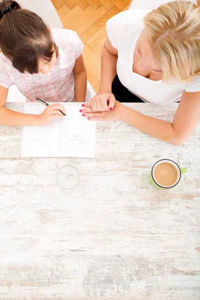 Moeder haar dochter met het huiswerk helpen — Stockfoto