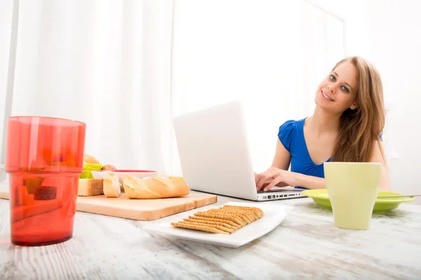 Jovem mulher usando um computador portátil, depois de ter o pequeno-almoço — Fotografia de Stock