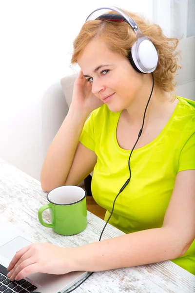 Young plus size woman listening to Audio while working on a lapt — Stock Photo, Image