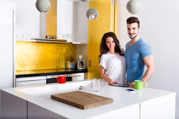 Pareja joven usando un Tablet PC en la cocina en casa —  Fotos de Stock