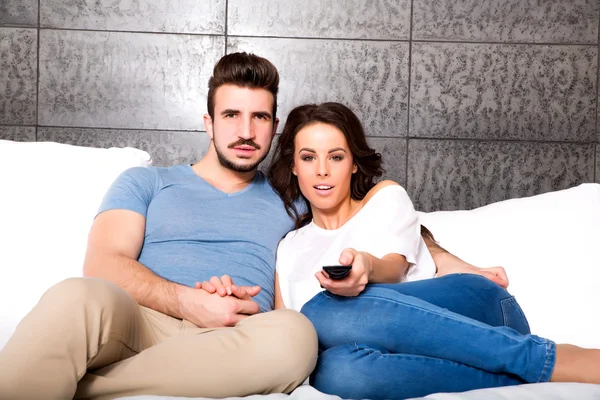 Pareja joven viendo televisión juntos en el sofá — Foto de Stock